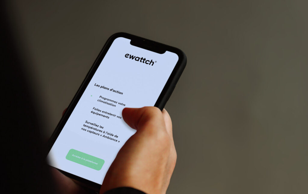 Utilisateur consultant sur smartphone l’application Ewattch affichant des recommandations et plans d’action pour améliorer la performance énergétique et le pilotage des équipements d’un bâtiment.