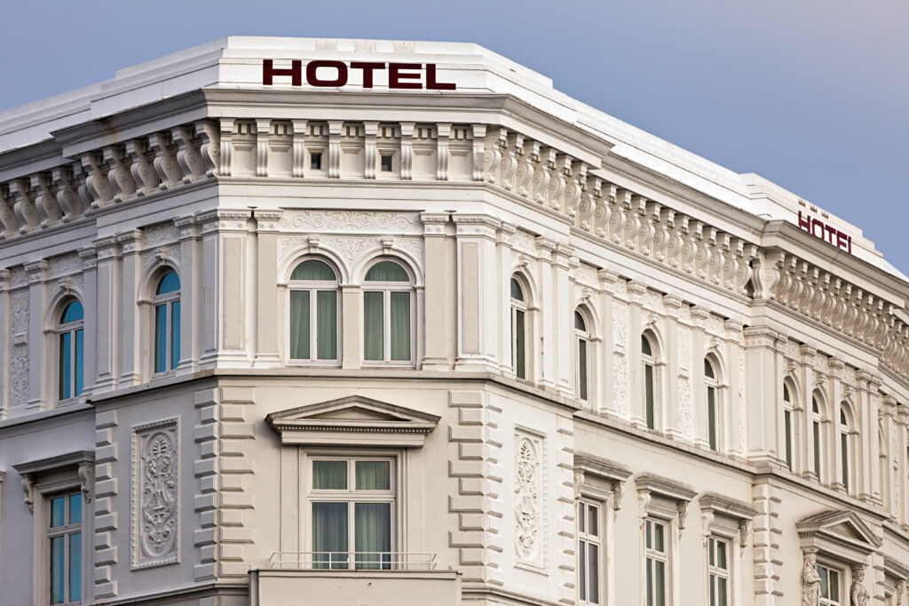 Facade of a classic-style hotel with windows and HOTEL sign in red letters