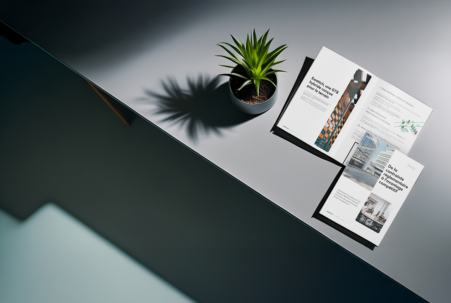 Livre blanc Ewattch ouvert sur une table avec une plante décorative, présentant des solutions de GTB hybride et de conformité réglementaire pour le Facility Management.