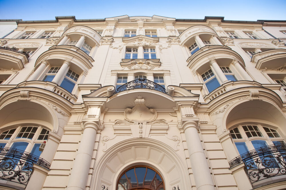 Façade majestueuse d’un hôtel de prestige avec colonnes, balcons ouvragés et architecture classique.