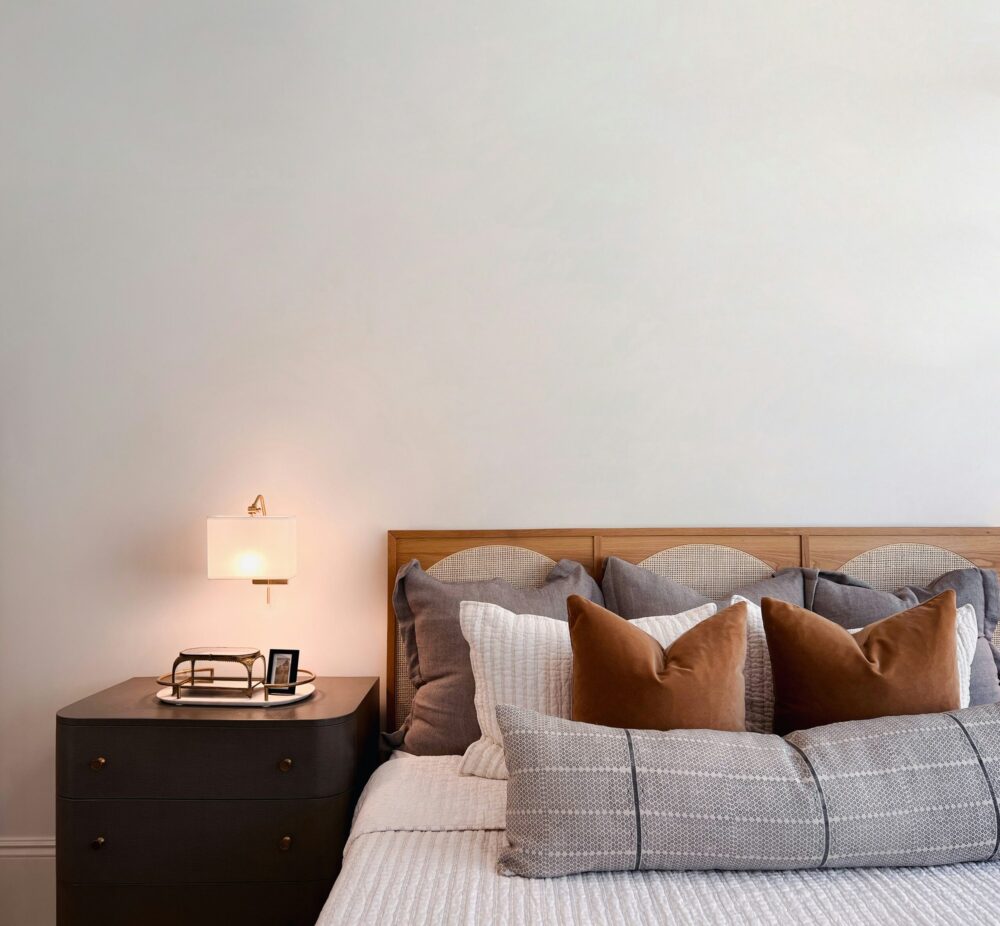 Chambre d’hôtel avec grand lit, linge de qualité, coussins décoratifs et éclairage chaleureux favorisant le confort des clients.