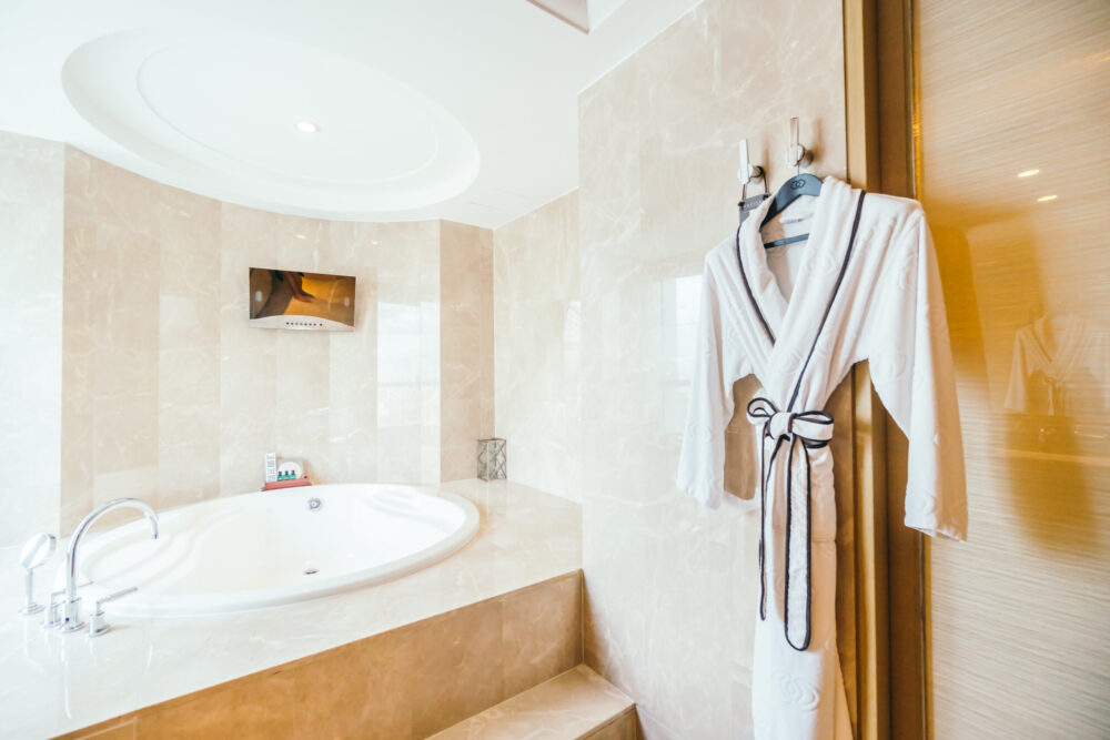 Salle de bain d’hôtel avec baignoire et peignoir suspendu.