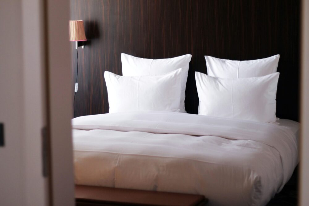 A king-size bed in an elegant hotel room with white linens and modern decor.