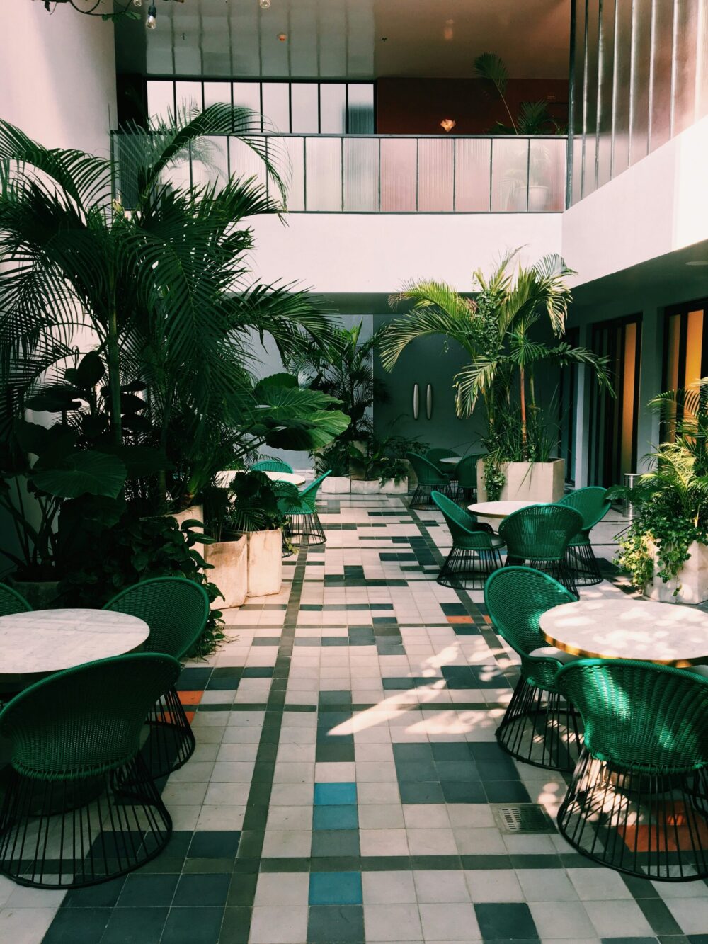 Espace détente d’hôtel avec patio intérieur, végétation et mobilier contemporain.