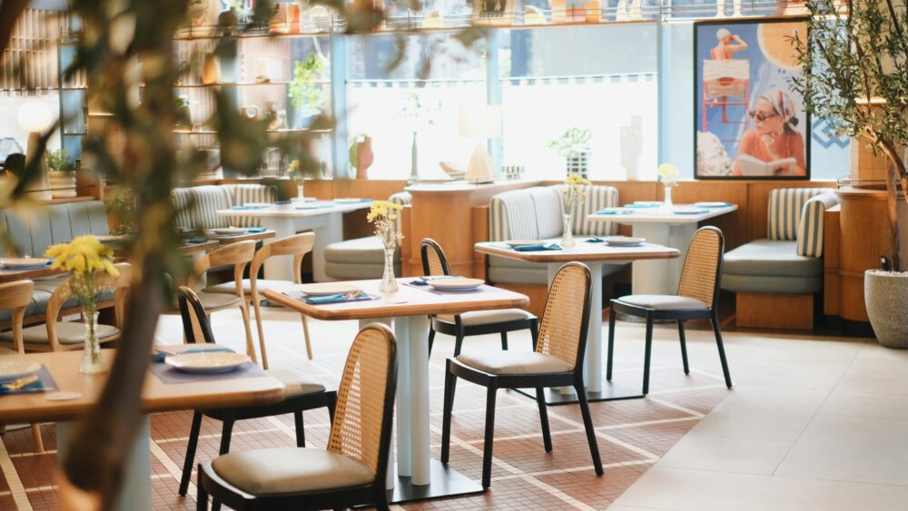 Salle de restaurant d’hôtel avec décoration moderne, tables dressées et ambiance conviviale.