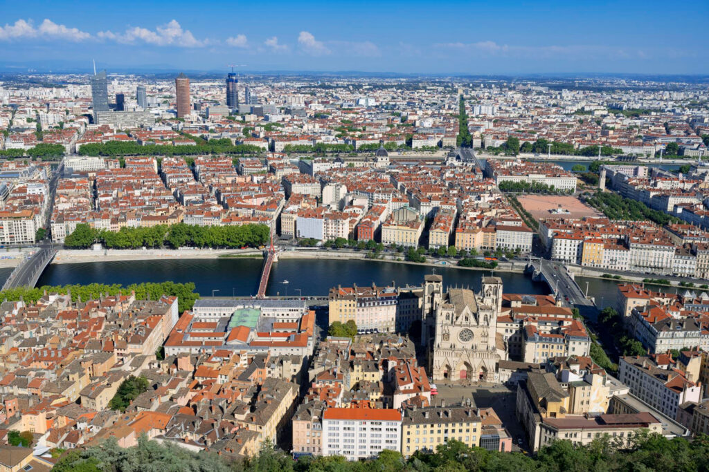 Vue aérienne d’une grande ville avec bâtiments, rivière et zones urbaines denses illustrant l’environnement tertiaire et hôtelier.