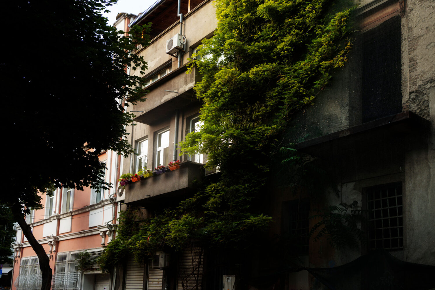 An urban building with greenery on its facade and architecture that incorporates natural elements in a residential or commercial setting.