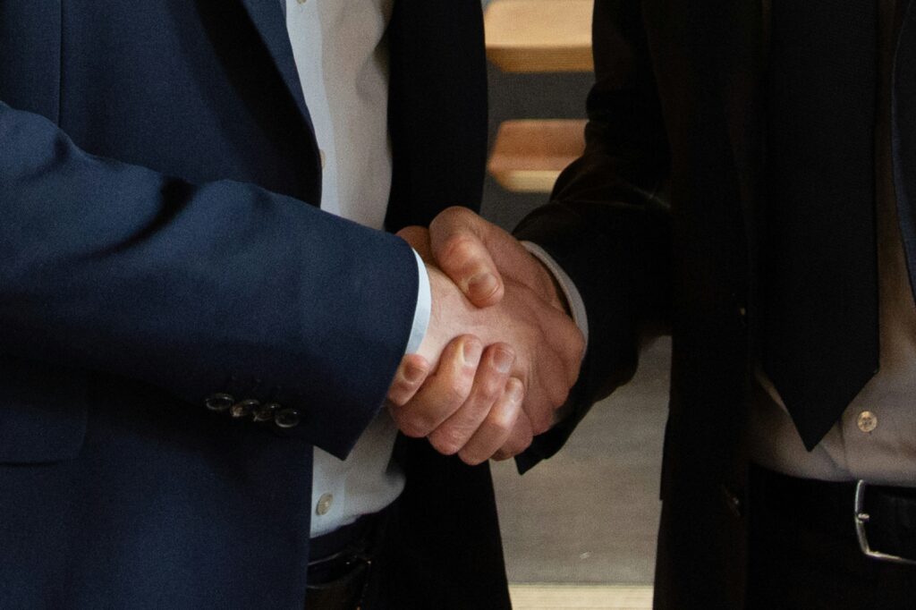 Poignée de main entre deux professionnels symbolisant la collaboration, l’accompagnement et la confiance dans la réussite d’un projet d’optimisation énergétique et de pilotage technique.