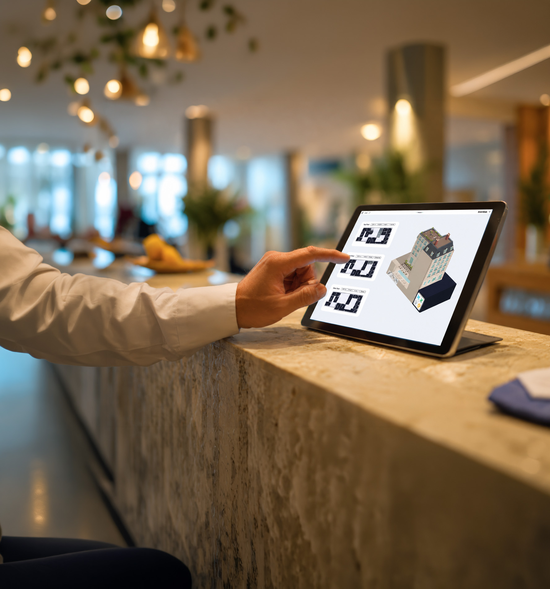 Gestionnaire hôtelier utilisant une tablette pour configurer les chambres et piloter les équipements d’un établissement via une interface numérique.