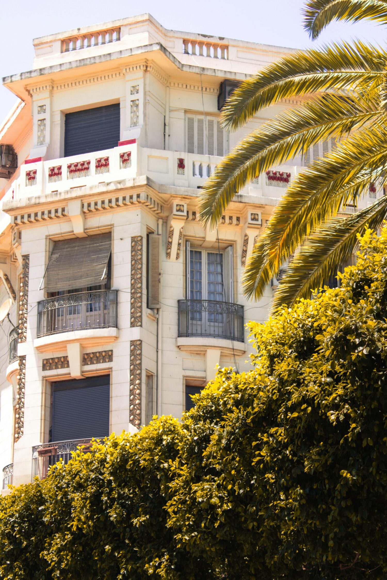 The facade of a boutique hotel featuring elegant architecture, balconies, and landscaped grounds with trees.